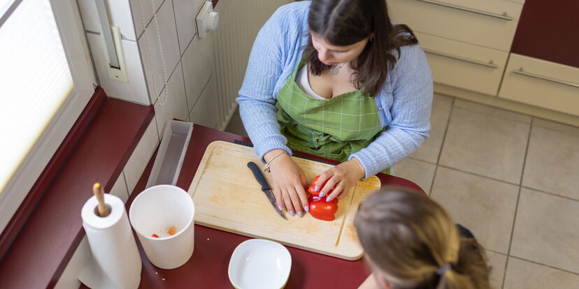 Blick von oben: eine Teilnehmerin fphlt eine Paprika auf einem Schneidebrett.