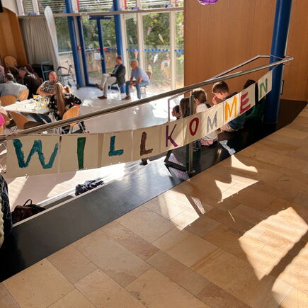 ein buntes Banner heißt in der Aula neue Schüler*innen Wilkommen.
