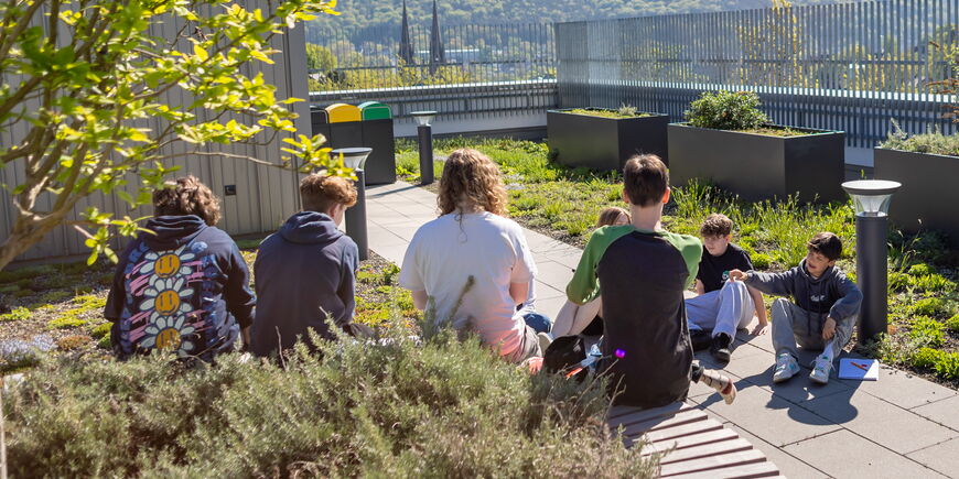 Mehrere Schüler*innen sitzen auf der Dachterrasse.