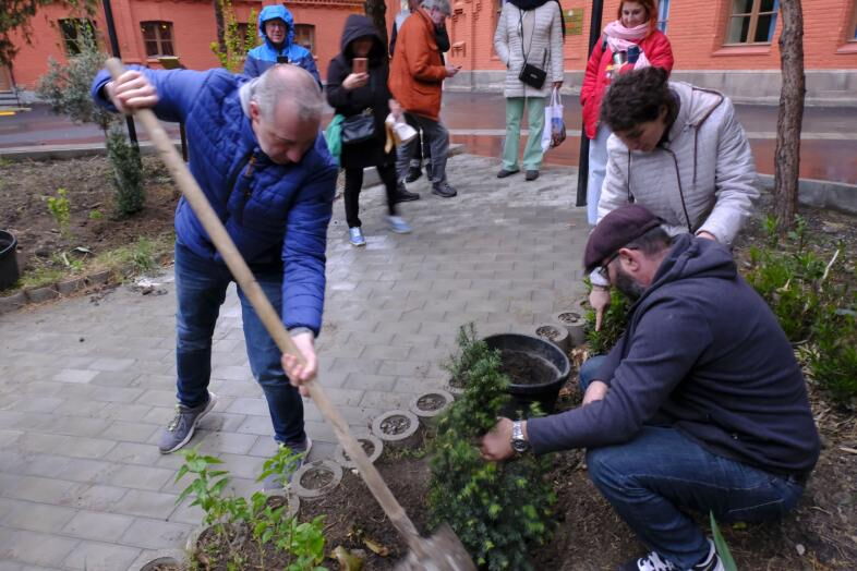 Der Vorstand der blista, Patrick Temmesfeld, pflanzt zusammen mit Frau Gachechiladse, der Schulleiterin der Schule vor Ort, einen kleinen Baum. Herr Temmesfeld schwingt dabei den Spaten, Frau Gachechiladse zeigt den genauen Ort an.
