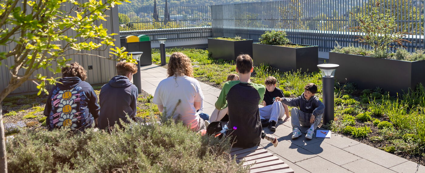 Mehrere Schüler*innen sitzen auf der Dachterrasse.