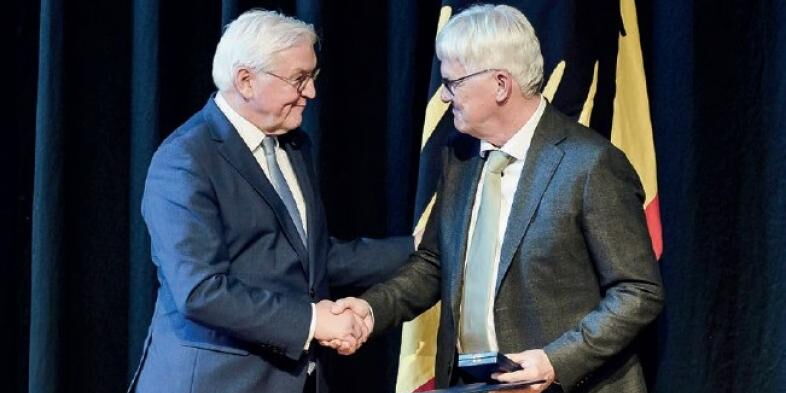 Bundespräsident Frank-Walter Steinmeier schüttelt Claus Duncker die Hand, im Hintergrund eine Deutschlandflagge.