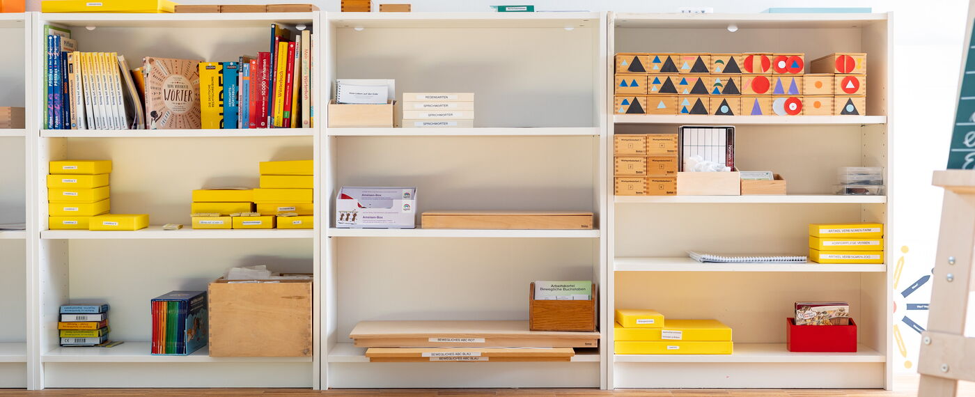 In verschiedenen weißen Regalen sind bunte Materialien sortiert.