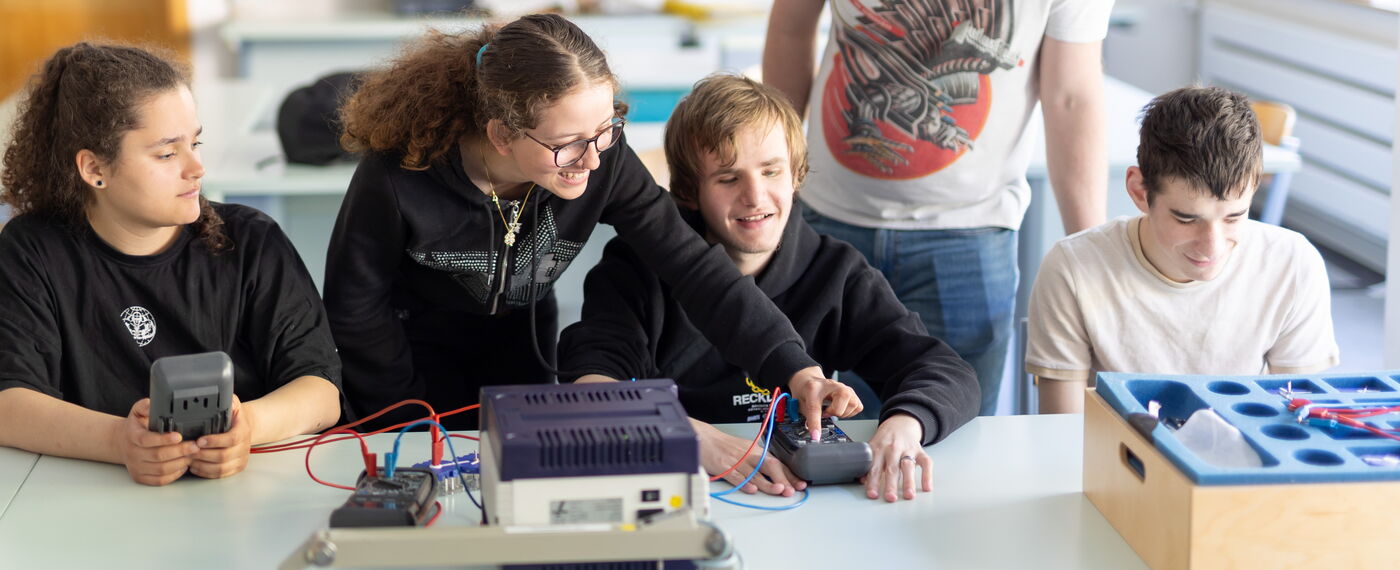 Vier Schüler:innen und ein Lehrer im Physik-Unterricht