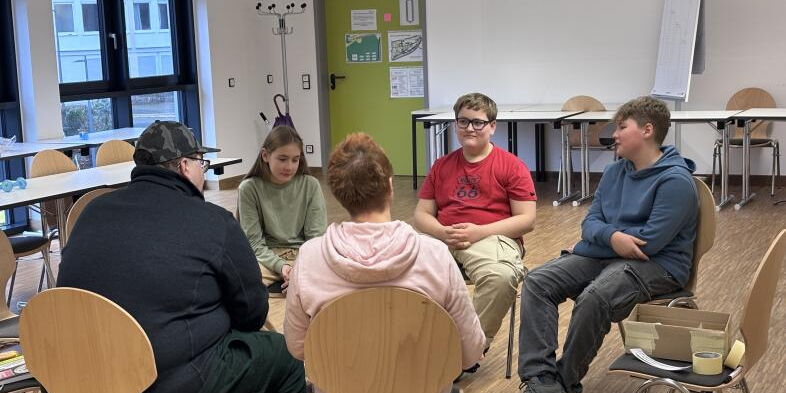 Fünf Menschen sitzen im Bielschowsky-Raum auf Stühlen im Kreis und scheinen zu diskutieren.