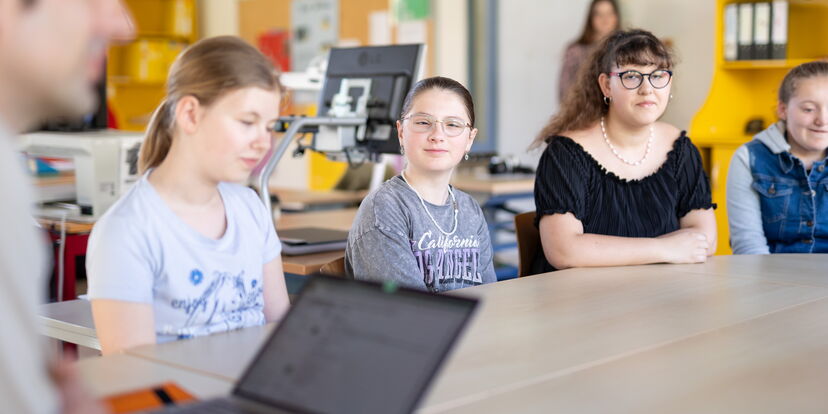 Vier Schüler*innen sitzen an einem Tisch.