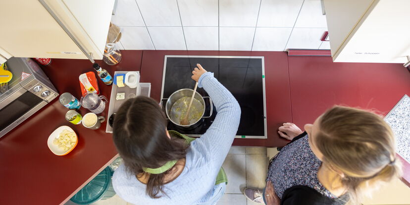 Blick auf den Herd von oben: eine Teilnehmerin rührt in einem Kochtopf.