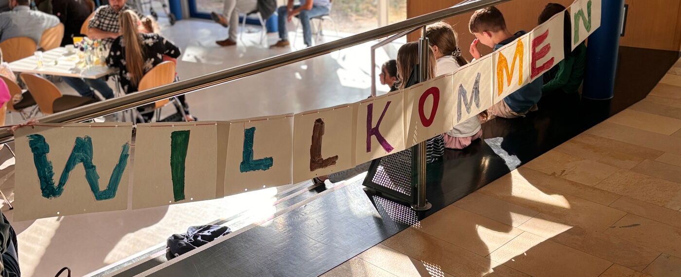 ein buntes Banner heißt in der Aula neue Schüler*innen Wilkommen.
