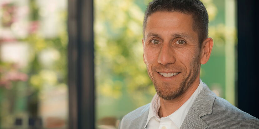 Das Portraitfoto zeigt Internatsleiter Daniel  lächelt freundlich in die Kamera. Er hat kurze braune Haare und einen drei-Tage-Bart. Er ist mit Anzug und weißem Hemd gekleidet.