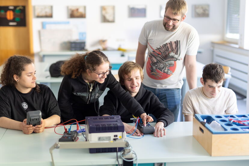 Vier Schüler:innen und ein Lehrer im Physik-Unterricht