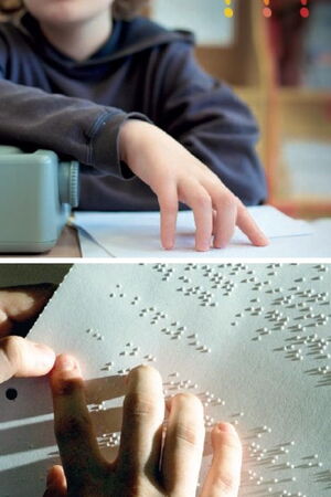 Ein Kind sitzt vor einer Schreibmaschine und liest Brailleschrift.