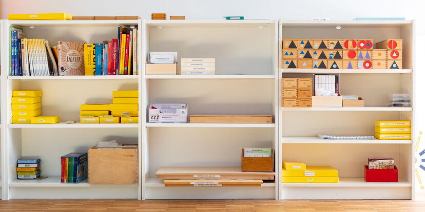 In verschiedenen weißen Regalen sind bunte Materialien sortiert.