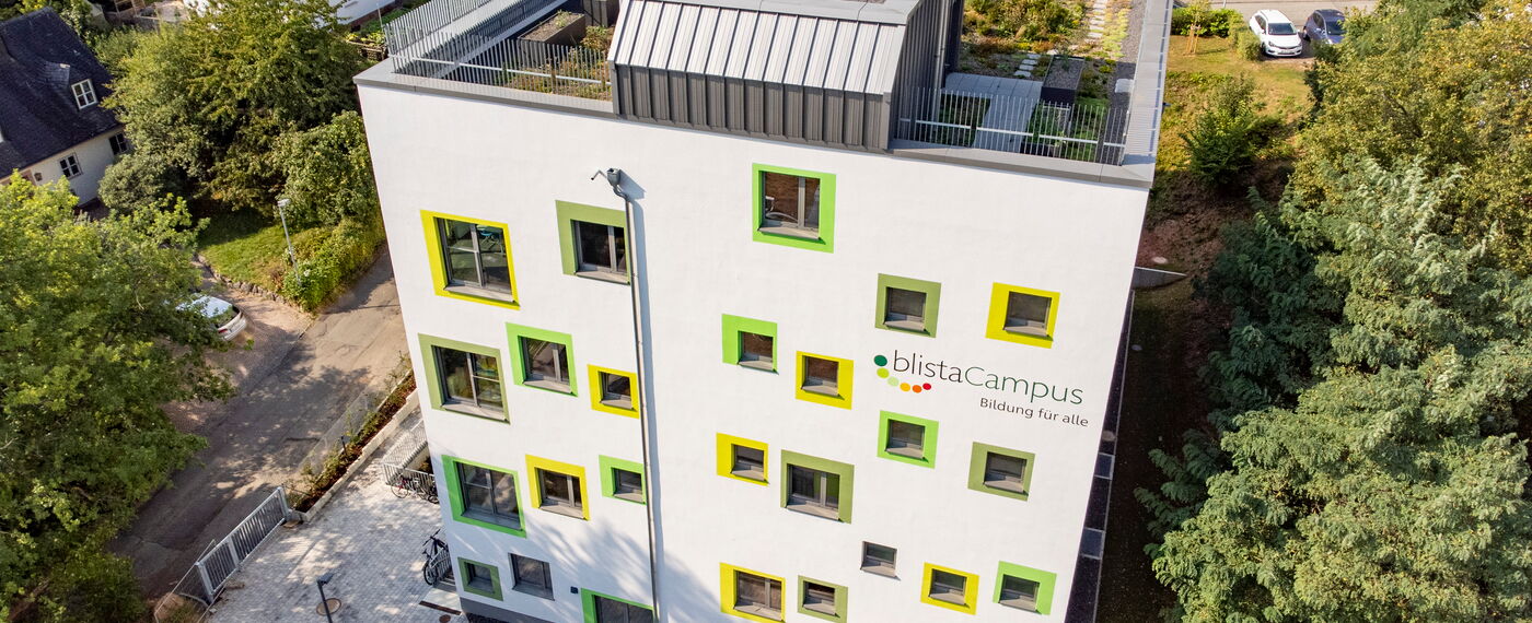 Das Schulgebäude der Montessorischule mit seinen grün umrandeten, verspielt angeordneten Fenstern aus der Luft