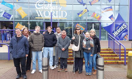 Die 6 Teilnehmenden der Englandfahrt mit ihren Lehrkräften stehen vor dem Eingang der Cadbury World