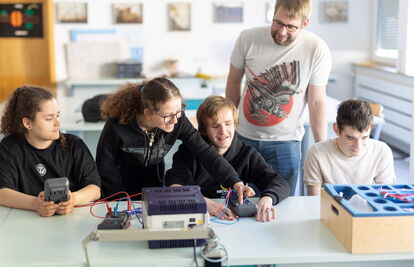 Vier Schüler:innen und ein Lehrer im Physik-Unterricht